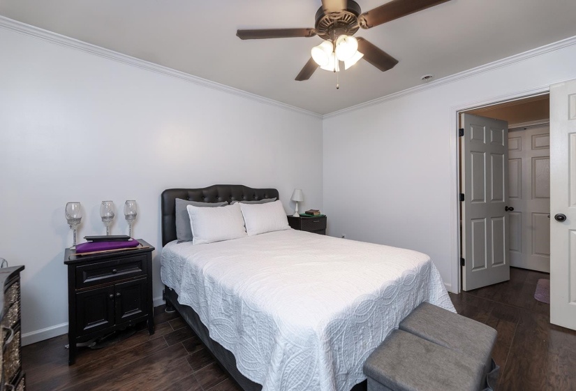 Bedroom with dark wood finished floors, ornamental molding, and a ceiling fan