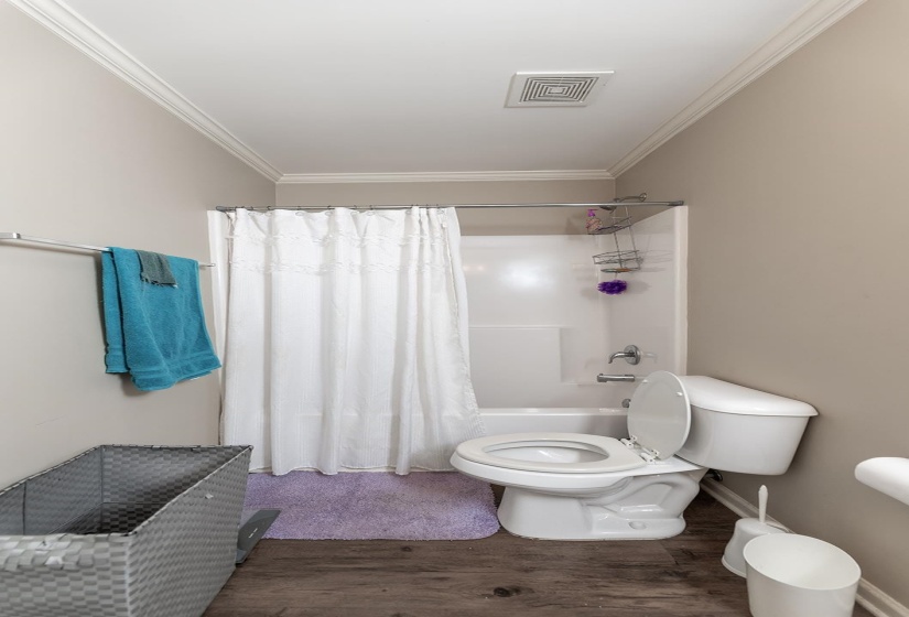 Bathroom featuring wood finished floors, shower / bath combo, and ornamental molding