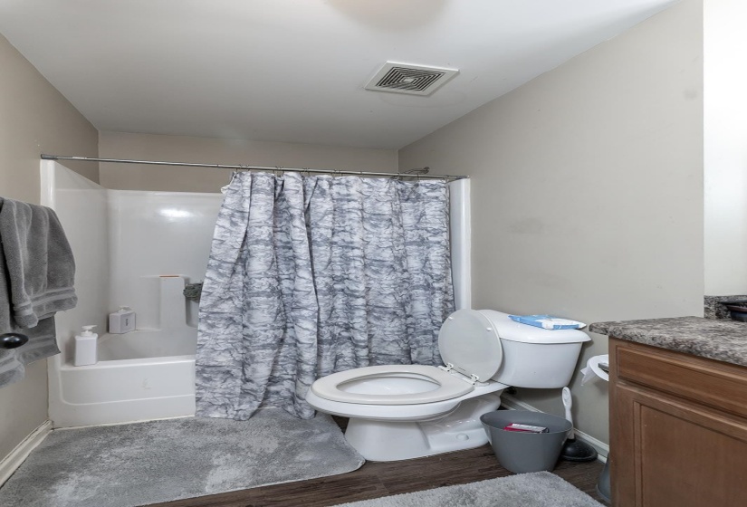 Full bath with shower / bath combination with curtain, vanity, and wood finished floors