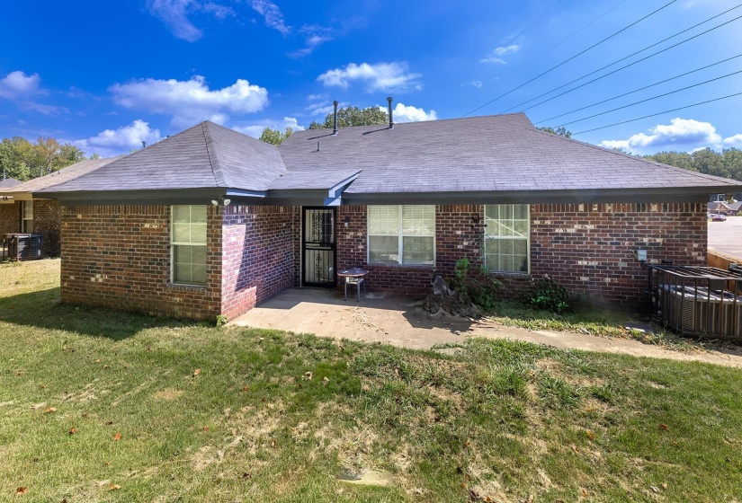 Back of property with a yard, brick siding, and a patio