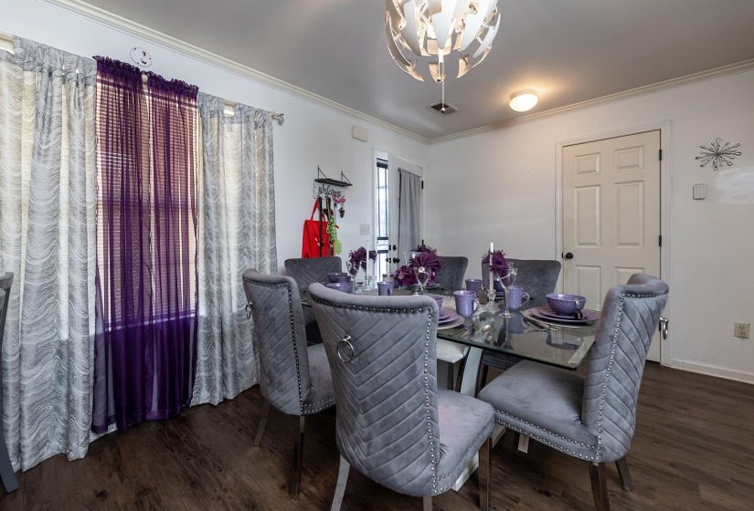 Dining room with crown molding, a chandelier, and dark wood-style flooring