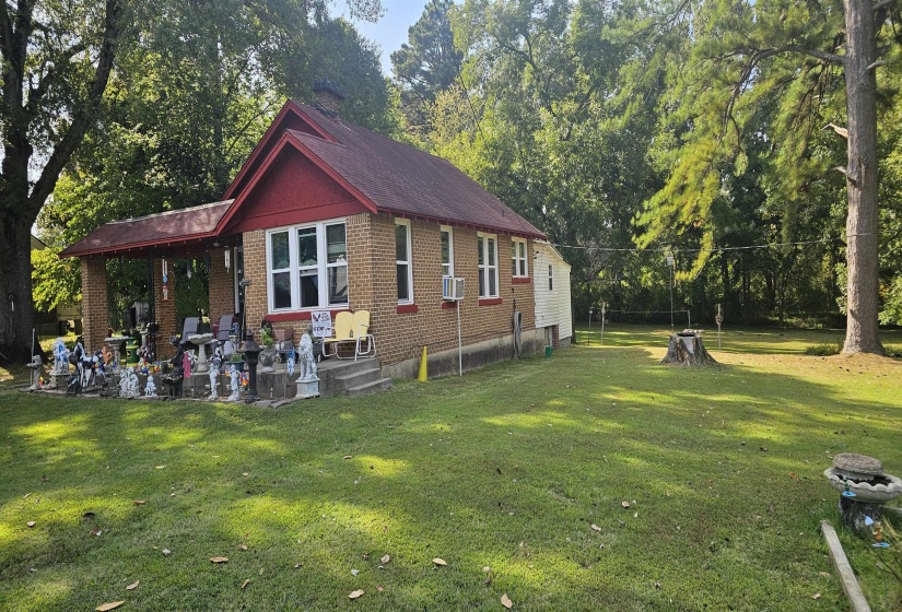 View of side of property with a yard, brick siding, and view of wooded area