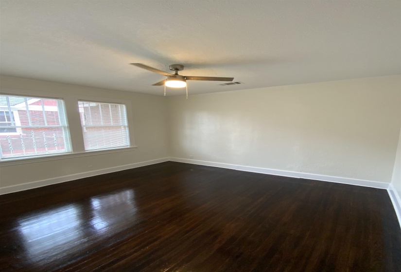 Empty room featuring dark wood-style flooring and a ceiling fan