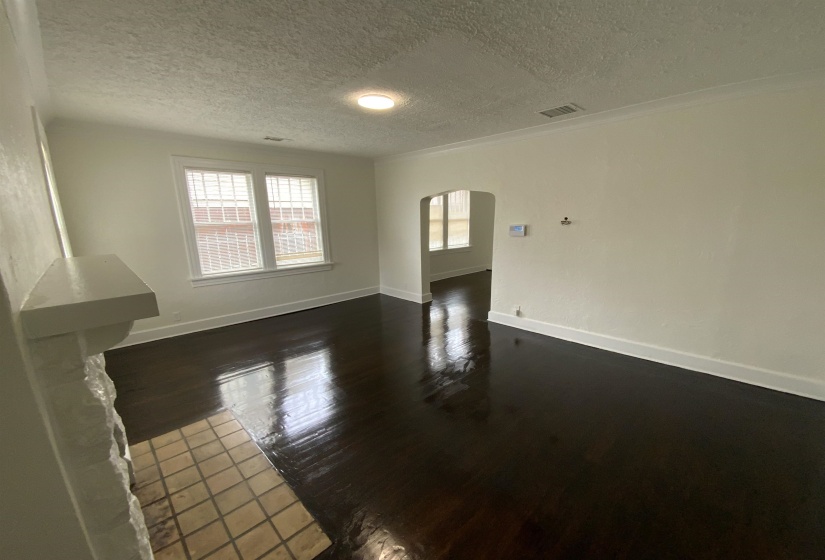 Unfurnished living room featuring arched walkways, dark wood finished floors, and a textured ceiling