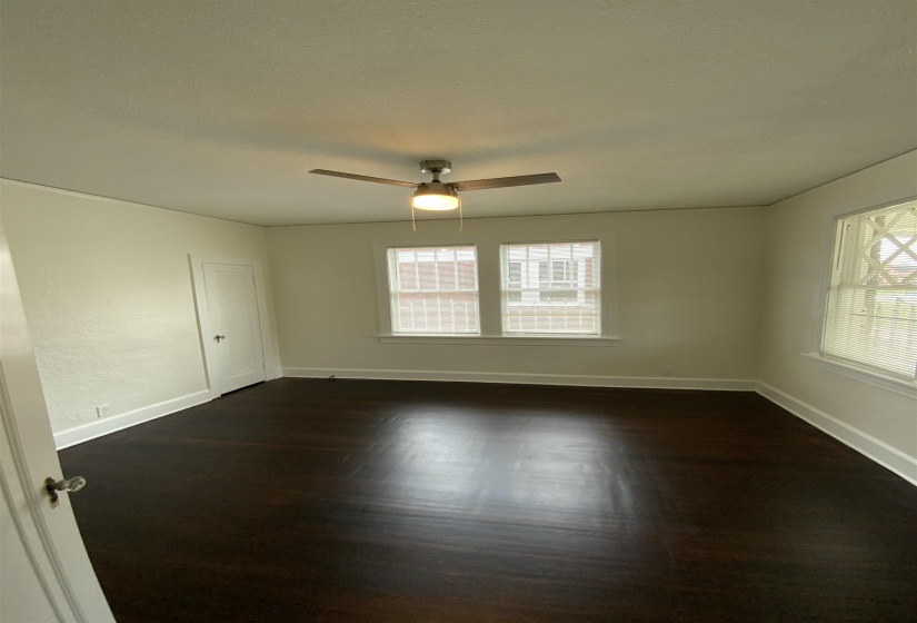 Unfurnished room featuring dark wood-style flooring and ceiling fan