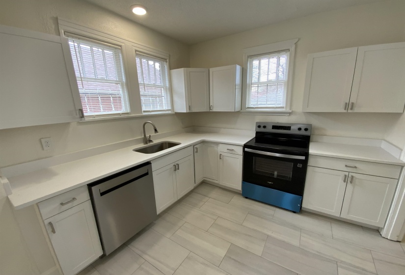 Kitchen with electric range, white cabinetry, and dishwasher