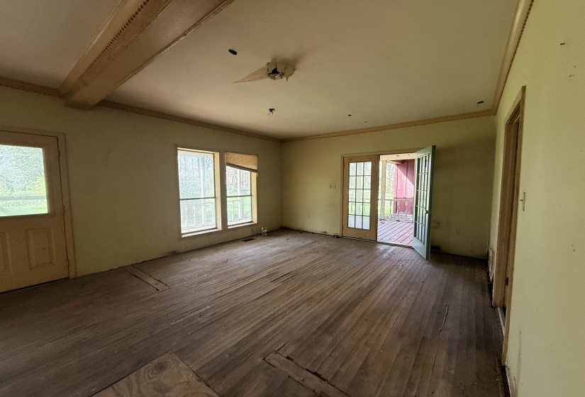 Unfurnished living room with dark wood-type flooring, plenty of natural light, and ornamental molding