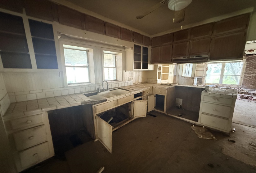 Kitchen featuring tile counters, ceiling fan, a peninsula, and backsplash