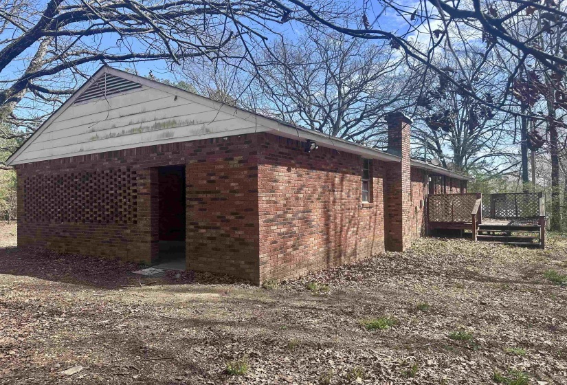 View of home's exterior with brick siding, a chimney, and a deck
