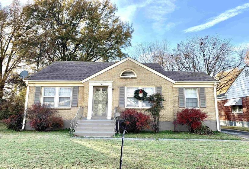 Bungalow-style house featuring a shingled roof, a front lawn, and brick siding