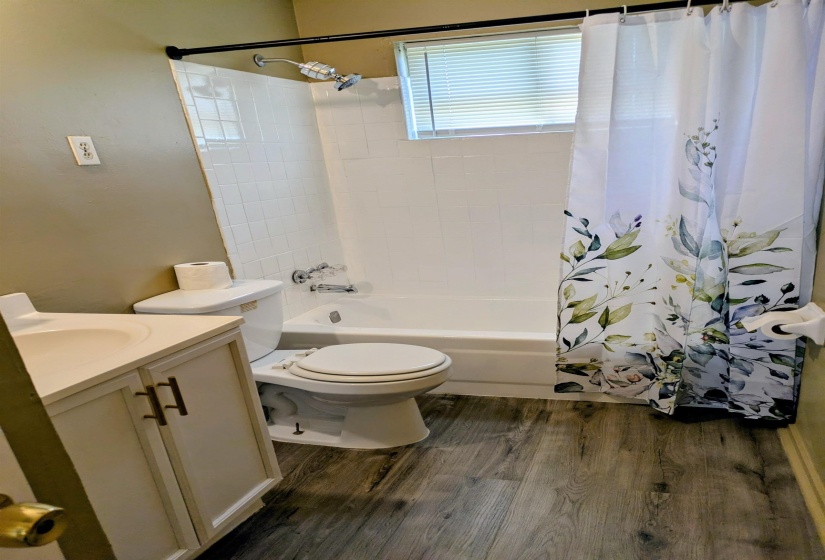 Full bathroom with vanity, shower / bath combo with shower curtain, and dark wood-type flooring