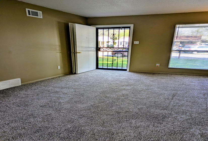 Carpeted living room with baseboards and a textured ceiling