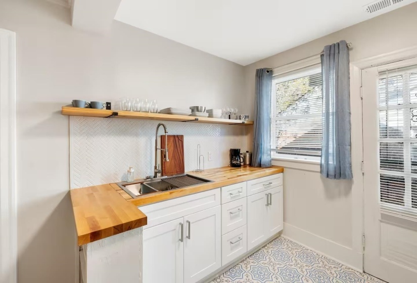 Bar area with butcher block countertops, white cabinetry, open shelves, and decorative backsplash