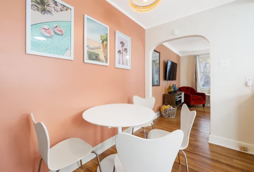 Dining space featuring arched walkways, wood finished floors, and crown molding