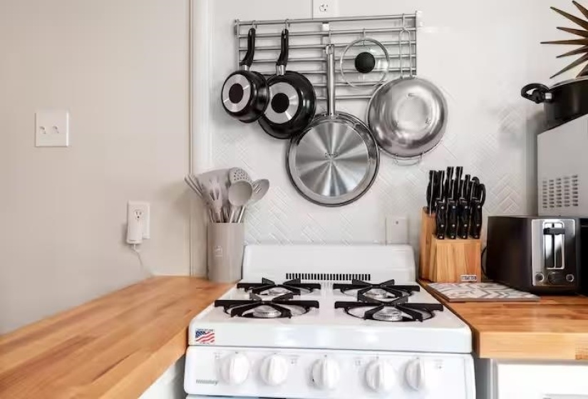 Kitchen view of butcher block countertops, white gas stove, white cabinets, and decorative backsplash