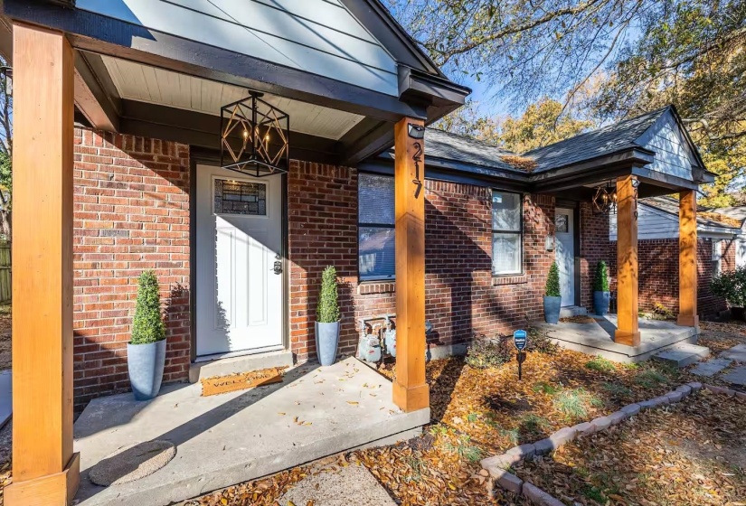 Doorway to property with brick siding and covered porch