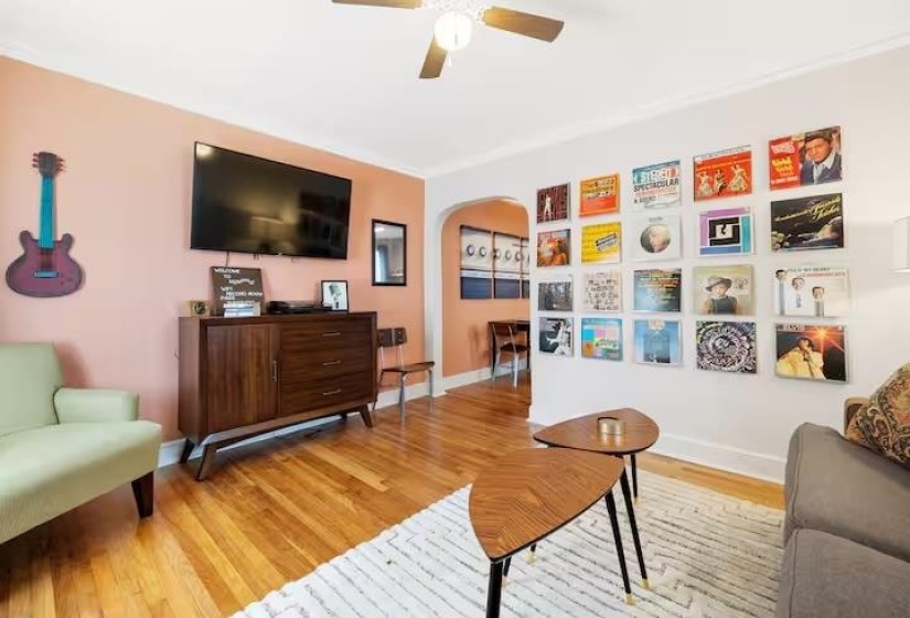 Living area featuring light wood-type flooring, arched walkways, and a ceiling fan