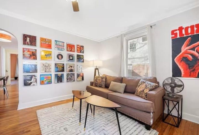 Sitting room featuring light wood-type flooring, arched walkways, and ceiling fan