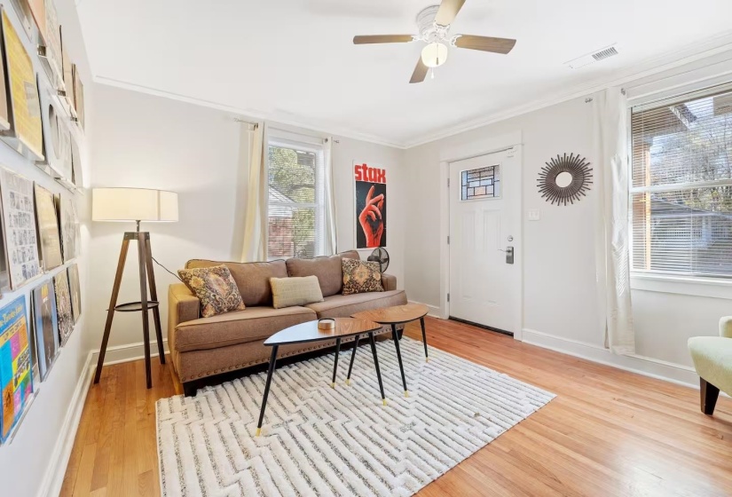 Living room featuring light wood-type flooring, ceiling fan, and crown molding