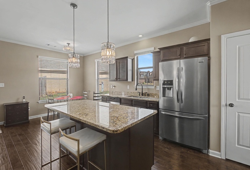 Kitchen with dark wood finish cabinetry, stainless steel appliances, a breakfast bar, a center island, and light stone countertops