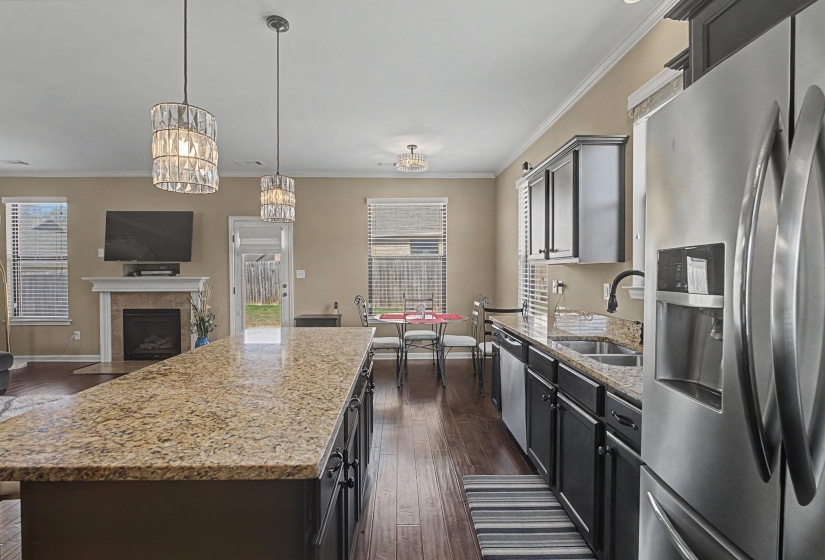 Kitchen featuring stainless steel appliances, light stone countertops, dark wood-style floors, open floor plan, and crown molding