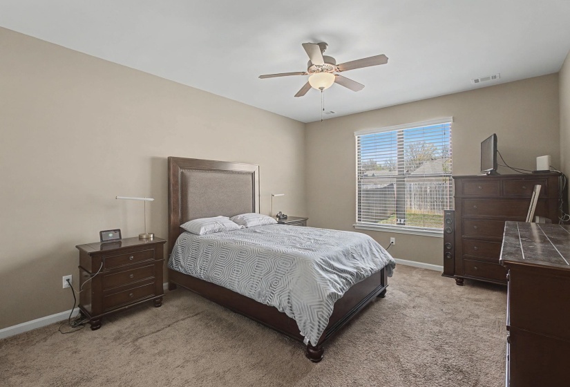 Bedroom with light colored carpet and a ceiling fan