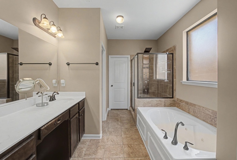 Bathroom featuring vanity, a stall shower, and a tub with jets