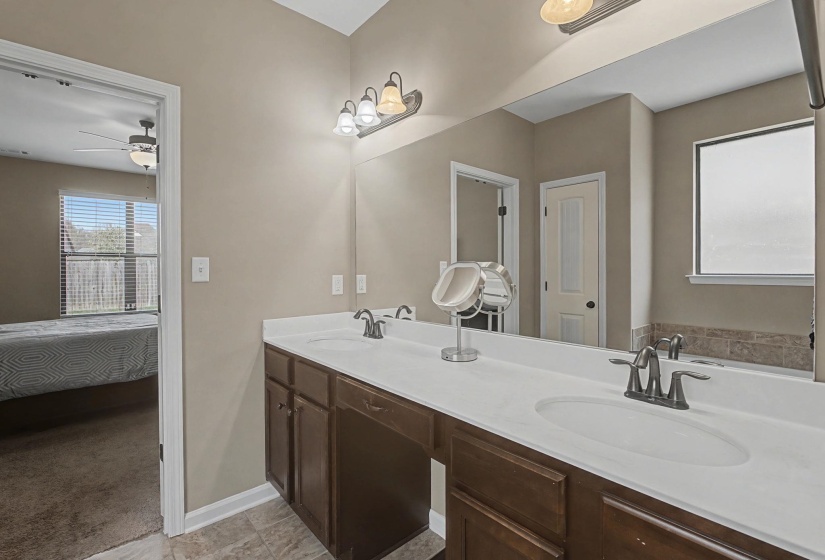 Bathroom featuring ensuite bath, double vanity, and ceiling fan