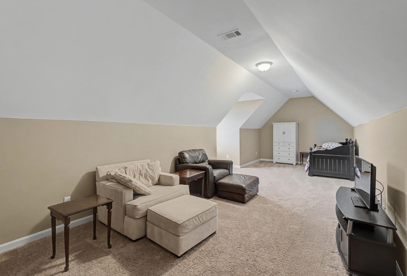 Bedroom featuring light colored carpet and vaulted ceiling