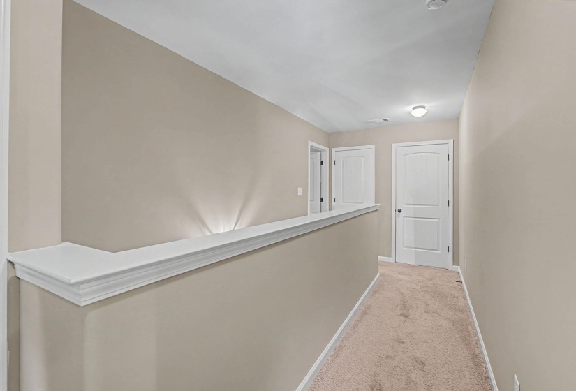 Corridor with light colored carpet and baseboards