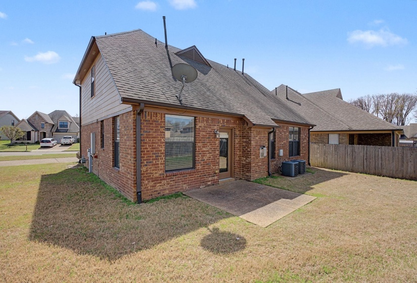 Rear view of house featuring a patio area, brick siding, and a shingled roof