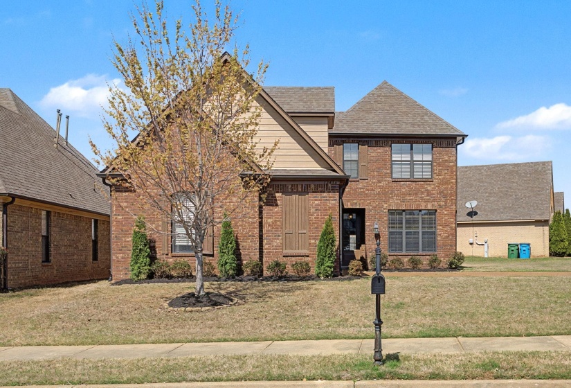 View of front facade featuring roof with shingles, a front lawn, and brick siding