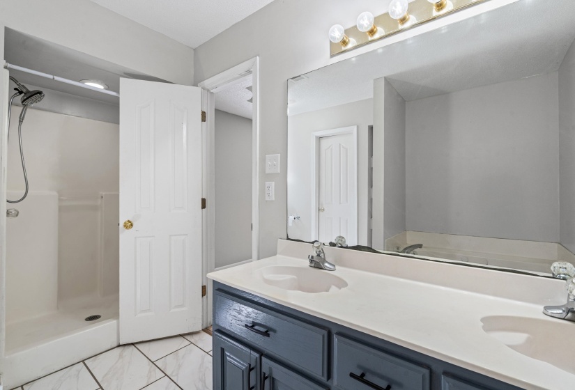 Bathroom with double vanity, a stall shower, and light marble finish floors