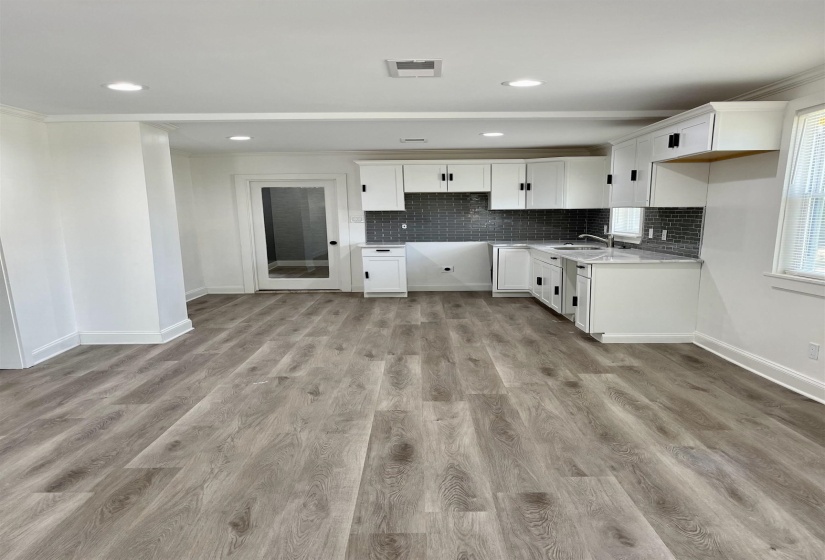 Kitchen with white cabinetry, decorative backsplash, light wood-type flooring, crown molding, and recessed lighting