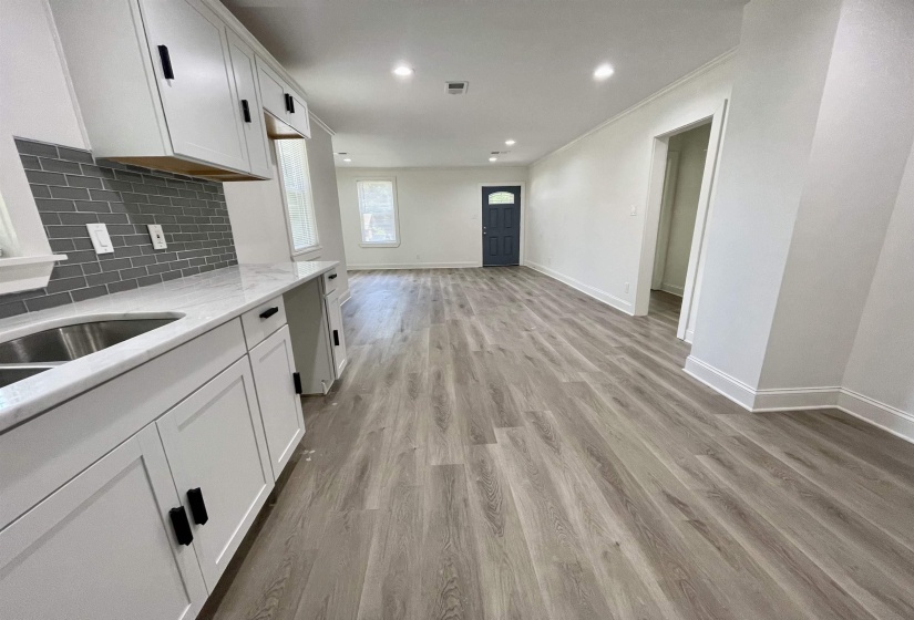 Kitchen featuring white cabinets, light stone countertops, light wood-style flooring, recessed lighting, and tasteful backsplash