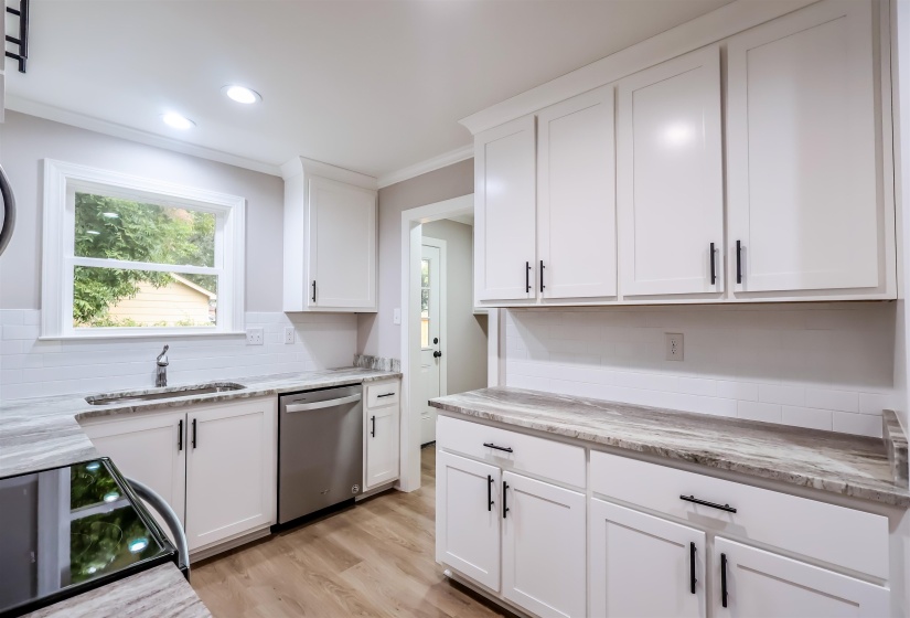 Kitchen with white cabinets, range with electric cooktop, stainless steel dishwasher, light wood finished floors, and crown molding