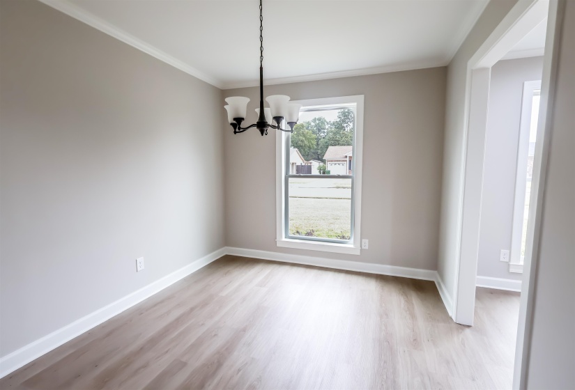 Unfurnished dining area featuring a chandelier, light wood-style floors, and ornamental molding