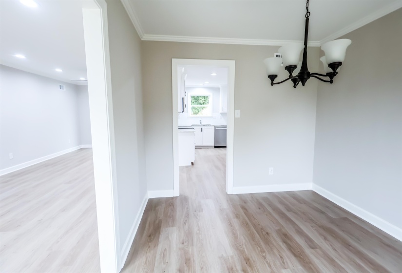 Unfurnished dining area with a chandelier, light wood-style floors, ornamental molding, and recessed lighting