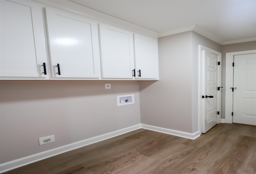 Laundry room featuring light wood-style floors, hookup for a washing machine, crown molding, and cabinet space