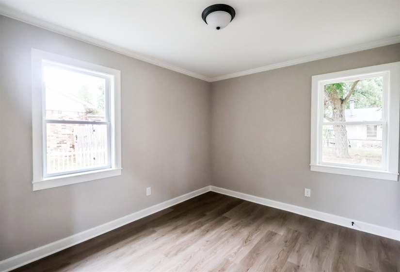 Unfurnished room featuring light wood finished floors, plenty of natural light, and crown molding
