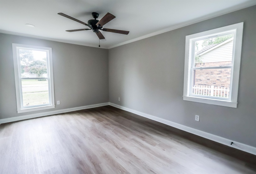 Spare room featuring light wood-style floors, crown molding, and ceiling fan