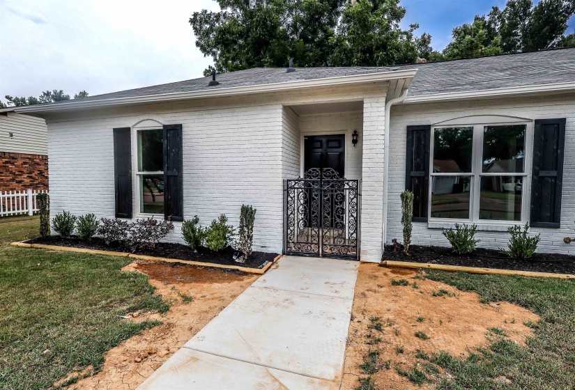 Entrance to property with brick siding, a gate, and roof with shingles