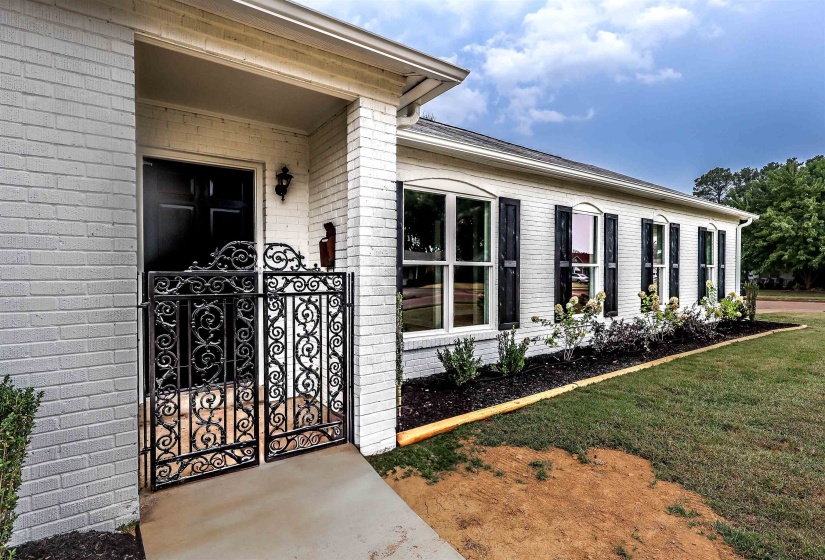 Doorway to property with brick siding and a lawn