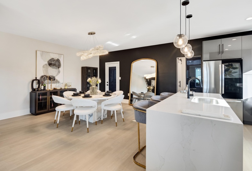 Kitchen featuring decorative light fixtures, light stone counters, a kitchen island with sink, a breakfast bar, and light wood-style flooring