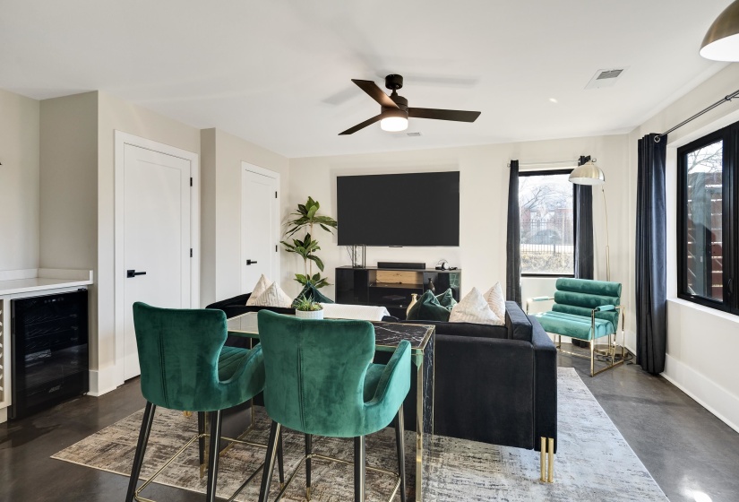 Living room featuring finished concrete flooring, beverage cooler, and ceiling fan