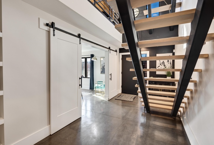 Hallway with finished concrete floors, a barn door, and stairs