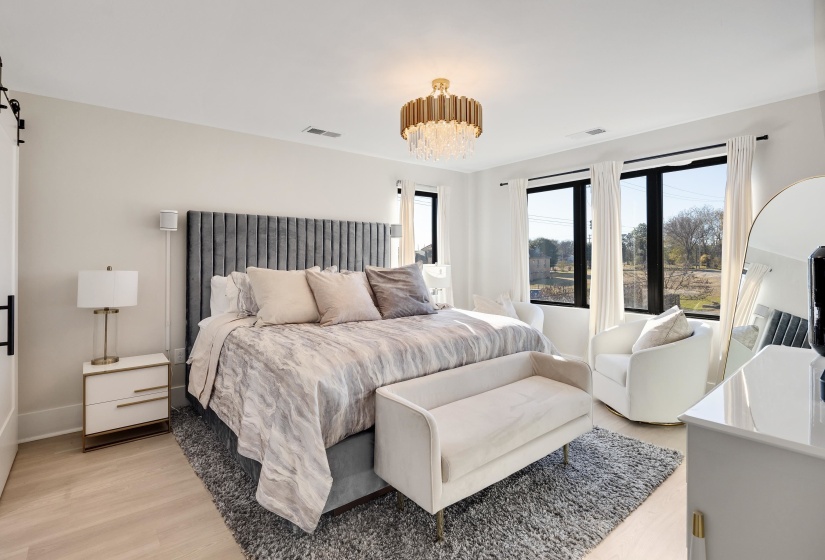 Bedroom with light wood finished floors, a chandelier, and a barn door