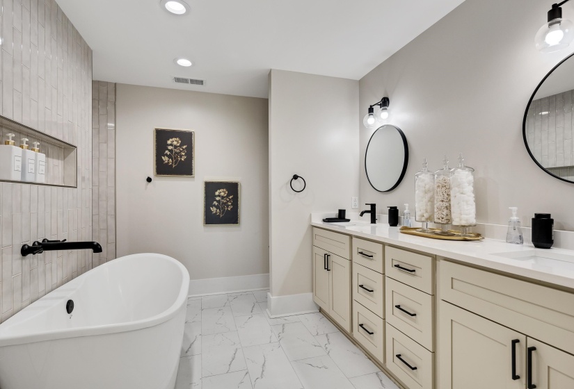 Full bath featuring a soaking tub, light marble finish floors, double vanity, and recessed lighting