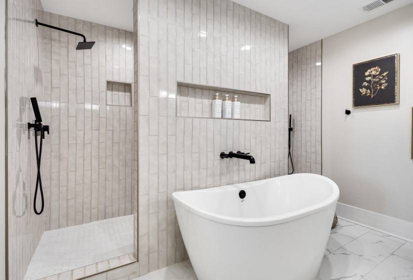 Full bathroom featuring marble look tiles, a freestanding bath, and a walk in shower