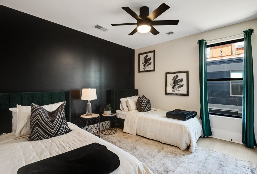 Bedroom with wood finished floors, a ceiling fan, and an accent wall